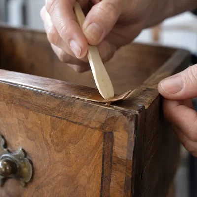 Dépoussiérage au pinceau doux d’un décor sculpté sur un meuble en bois patiné 1a