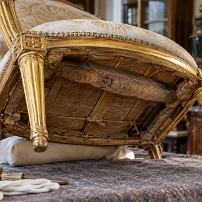 Marques aux fers - Dessous d’un fauteuil ancien en bois doré, montrant une marque de propriété sur une traverse 1